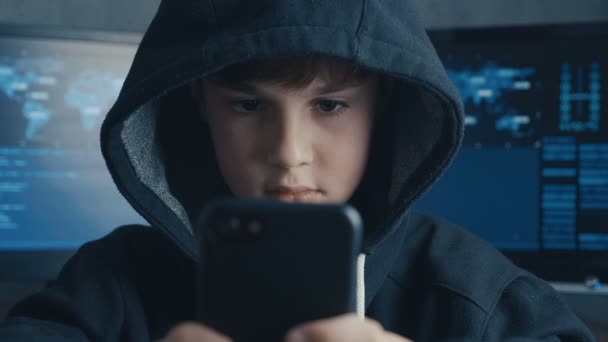 フード付きの若いハッカーの子供をハイジャックするスマート フォンのデバイスを使用しています。サイバー スペースで天才天才少年ハック システム. — ストック動画