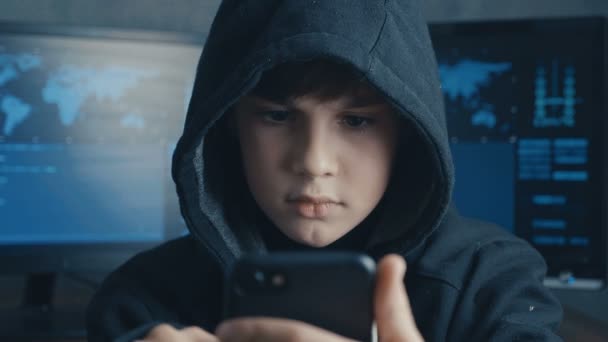 Young hooded boy using a smartphone device. Portrait of Genius boy wonder hacks system at cyberspace. — Stock Video