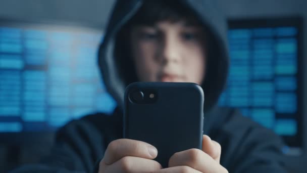 Młodzi z kapturem chłopiec przy użyciu urządzenia smartphone w centrum danych. Portret Genius boy wonder hacki systemu w cyberprzestrzeni. — Wideo stockowe