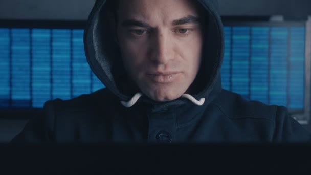 Nahaufnahme eines gefährlichen männlichen Hackers in Kapuze, der an einem Computer in einem Rechenzentrum arbeitet. Cybercrime-Konzept. — Stockvideo