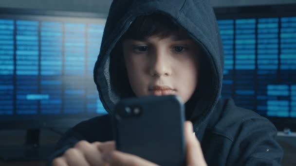 Niño encapuchado joven usando un dispositivo de teléfono inteligente. Retrato de genio chico maravilla hacks sistema en el ciberespacio . — Vídeos de Stock