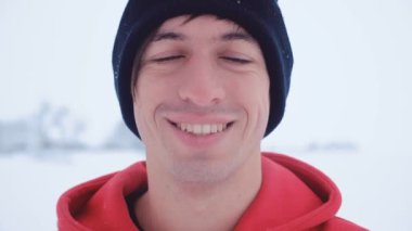 Çekici genç adam Close-up bak karlı kış soğuk havada gülümseyen kamera