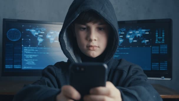 Jonge hooded hacker kind met behulp van een smartphoneapparaat om te kapen. Genie boy wonder hacks systeem in cyberspace. — Stockvideo