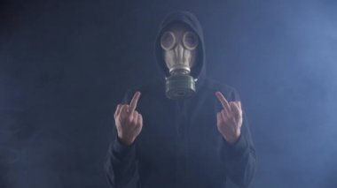 Gaz Maskeli adam orta parmak duman dolu karanlık bir odada gösterir..
