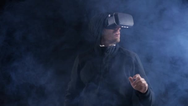 Onderdompeling in de virtuele realiteit. Young Man in Vr headset kijkt rond op zwarte achtergrond. — Stockvideo
