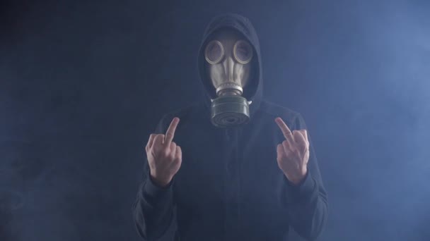 Mann mit Gasmaske zeigt Mittelfinger in verrauchtem dunklen Raum. — Stockvideo