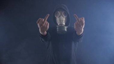 Gaz Maskeli adam orta parmak duman dolu karanlık bir odada gösterir..