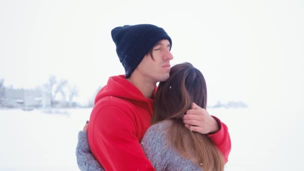 Молодой грустный мужчина обнимает свою жену. Эмоциональная влюбленная пара обнимается зимой на снежном фоне — стоковое видео