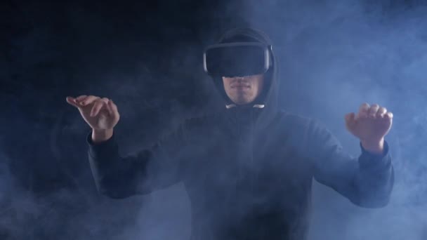 Homem obtendo experiência no uso de fone de ouvido VR em fundo escuro fumado. Dispositivo de realidade aumentada criando espaço virtual . — Vídeo de Stock