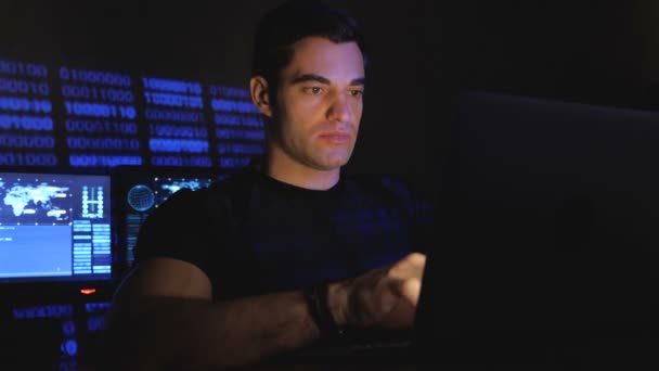 Красивий чоловік-програміст джик працює за комп'ютером вночі в офісі, наповненому екранами монітора — стокове відео