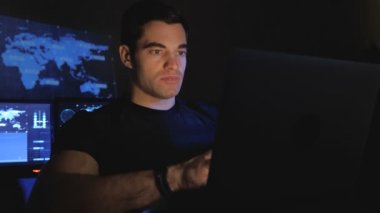 Yakışıklı erkek programcı geek bir veri merkezi monitör ekranlar ile doldurdu geceleri bir bilgisayarda çalışıyor