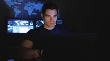 Yakışıklı erkek hacker programcı bir veri merkezi monitör ekranlar ile doldurdu geceleri bir bilgisayarda çalışıyor