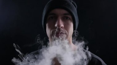 duman e-sigara vape yavaş çekimde siyah arka plan üzerine ile büyük bulutlar exhaling genç adam vaper