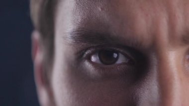 Kahverengi göz genç beyaz adamın gözünü açarak ve kamera lense siyah puslu arka planda arayarak kapatın.