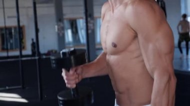 Spor salonunda ağırlık ile çalışan kaslı adam. Erkek vücut geliştirmeci pazı egzersiz yaparak dumbell ile çalışma dışarı.