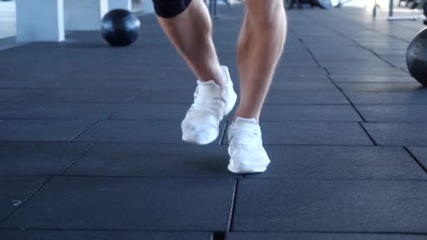 Close-up voetenwerk van jonge atletische mannelijke springen tijdens het oefenen met een springtouw. Atletische man uit te werken met een springtouw op sportschool — Stockvideo