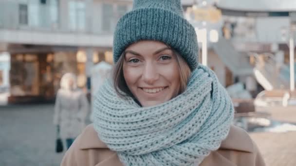 Retrato de linda jovem mulher em tricô cap ao ar livre. Jovem atraente é smilig na rua da cidade — Vídeo de Stock