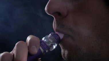 Adam vaper duman e-sigara vape yavaş çekimde siyah arka plan üzerine ile büyük bulutlar exhaling Close-Up