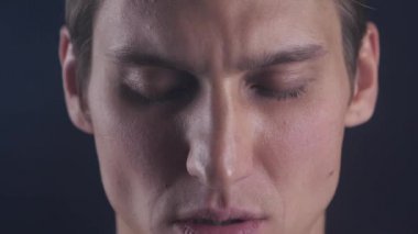 Genç adam portresi yakından gözlerini açar ve kamera siyah bir arka plan içine bakıyor