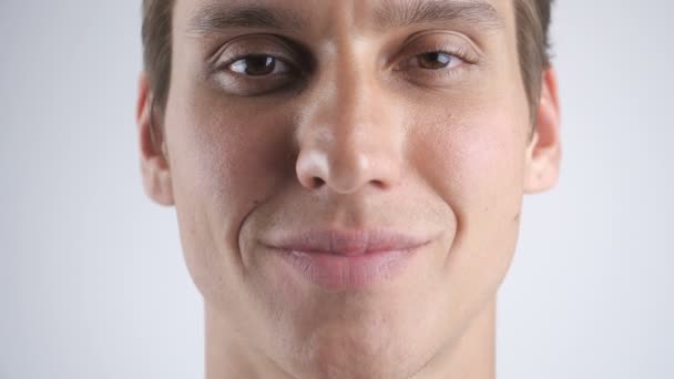 Gros plan Portrait de l'homme beau sourire souriant et regardant la caméra sur le fond blanc du mur. Ferme là. Intérieur . — Video