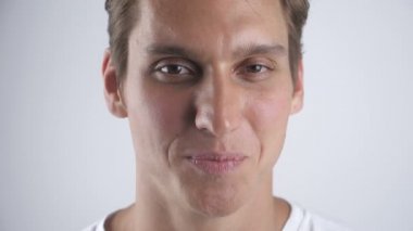 Gülümseyen ve beyaz duvar arka plan üzerinde kameraya poz gülümsüyor yakışıklı adam portresi. Yakın çekim. Kapalı.