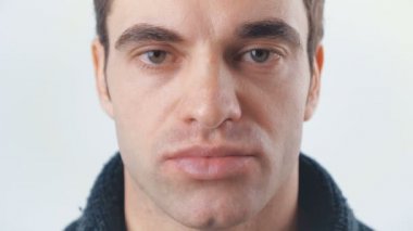 Yakışıklı olan beyaz arka plan üzerinde kameraya bakıyor. Memnun genç adam portresi.