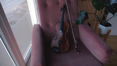 Pencere yakın odada sandalye yatarken yay ile keman. Sabit kam çekimi.