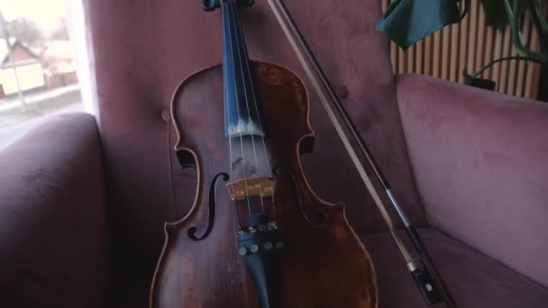 Violin med båge liggande stol i rummet nära fönster. Stadig cam skott. — Stockvideo