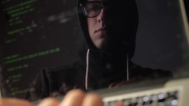 Double exposition : hacker homme dans des lunettes travaillant sur un ordinateur portable. Programmeur écrit la réflexion du code vert dans le moniteur — Video