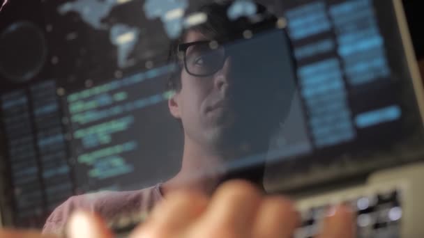 Double exposure: man programmer in glasses working at a laptop. Programmer writes blue code, reflection in the monitor — Stock Video