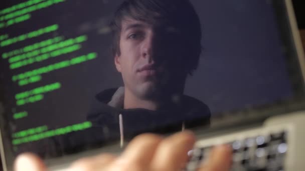 Double exposure: man hacker in glasses working at a laptop. Programmer writes green code reflection in the monitor — Stock Video