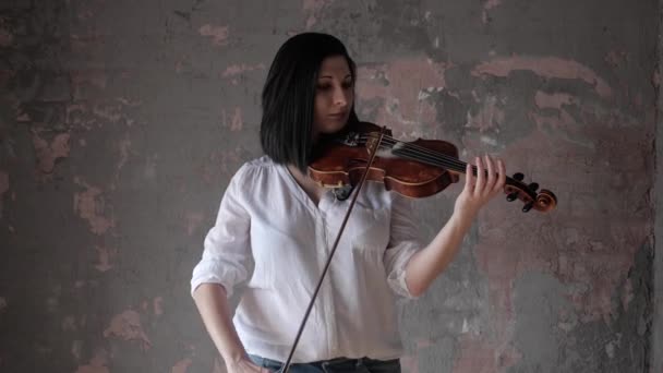 Красивая женщина-музыкант в белой рубашке играет на скрипке — стоковое видео