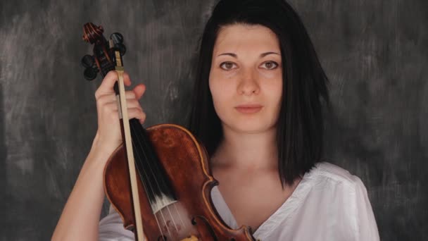 A női zenész portréja hegedűt tart kezében, és nézi a kamerát — Stock videók