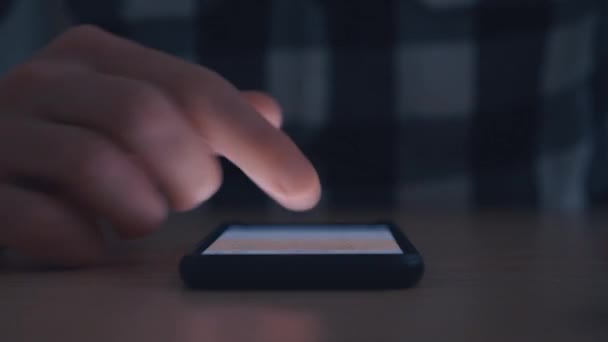 Чоловік прокручує палець на смартфон у темряві . — стокове відео