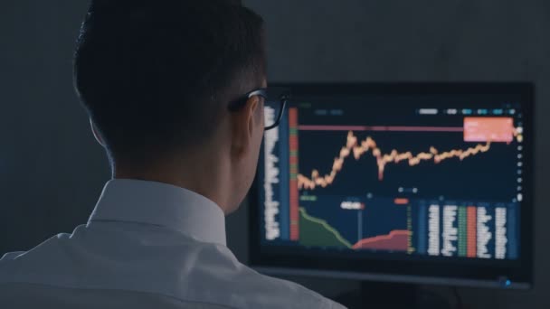 Empresario en camisa blanca y gafas analiza mercado de ventas. Vista posterior de Stockbroker está trabajando con el mercado financiero en la oficina nocturna . — Vídeos de Stock