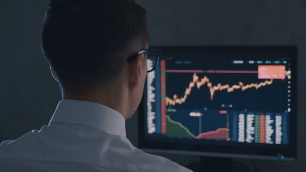 Homme d’affaires dans la chemise blanche et les lunettes analyse le marché des ventes. Vue de dos de Stockbroker travaille avec le marché financier au bureau de nuit. — Video