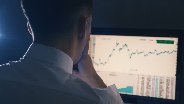 Homem de negócios está analisando estatísticas e gráficos de vendas mostrados em um monitor — Vídeo de Stock