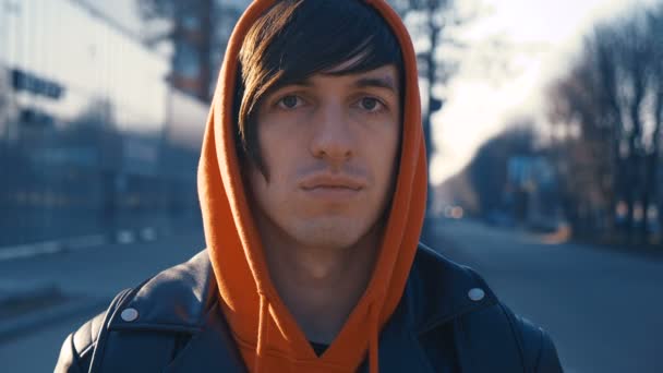 Verticale d'homme caucasien dans le sourire rouge de hoodie dans la ville au fond urbain de coucher du soleil — Video