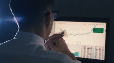 Beyaz gömlekli finansör işadamı bilgisayarda finans piyasasında aşırı çalışıyor. Adam yorgun ve baş ağrısı var