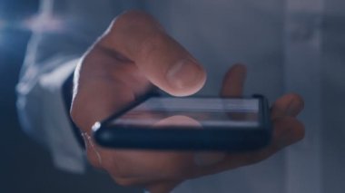 Gece büyük bir siyah smartphone üzerinde haber hattı kaydırma erkek el