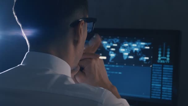 Обратный вид человека программиста в очках и белой рубашке, работающего за компьютером в дата-центре — стоковое видео