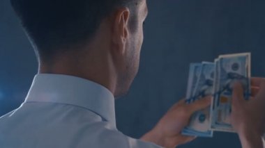 Amerikan banknotlarını sayan beyaz gömlekli işadamının arka görünümü. Adam sayma para, kar kavramı.