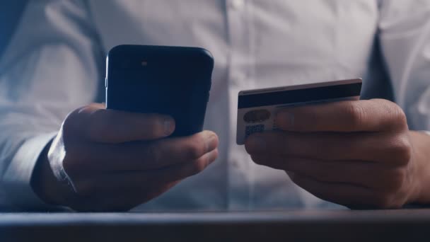 職場でクレジットカードでオンラインショッピングにスマートフォンを使用して白いシャツを着たビジネスマン。クローズ アップ. — ストック動画