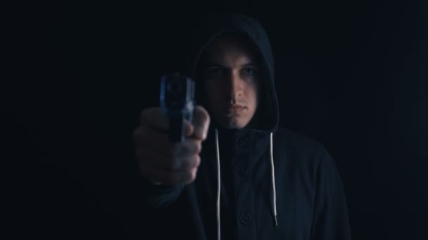 Farliga Hooded kriminella mål hans pistol på svart bakgrund — Stockvideo