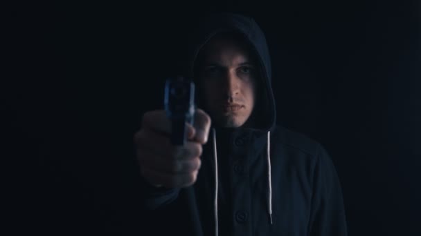 Farliga Hooded kriminella mål hans pistol på svart bakgrund — Stockvideo