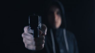 Kaputun paralı veya suikastçı siyah bir arka plan üzerinde bir tabanca ile hedefliyor.