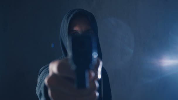 Peligroso encapuchado Criminal apunta su pistola sobre fondo negro — Vídeo de stock