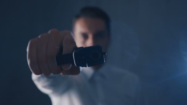 Hombre criminal con camisa blanca apuntando con un arma a una cámara. Céntrate en el arma . — Vídeos de Stock