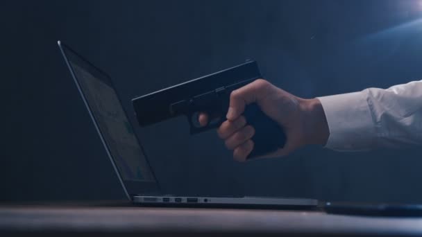 銃を持つ手は、ラップトップの画面を目指しています。サイバー犯罪の概念. — ストック動画
