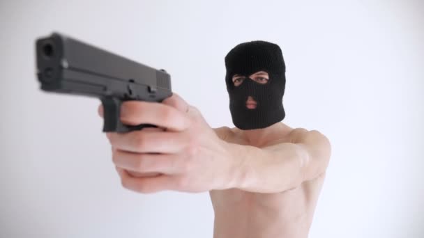 Терорист з голим торсом в Балаклаві націлений на пістолет на білому тлі — стокове відео